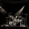 Dynamic concert scene with a drummer rocking on stage under spotlights in San Salvador.
