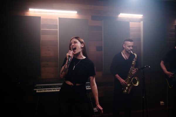 Energetic music band performing live in a recording studio with vocalist and saxophonist.