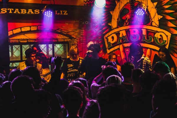 Live band performing in a lively and colorful club atmosphere with a cheering crowd enjoying the music.