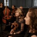 Group of orchestra musicians rehearsing with various instruments indoors.