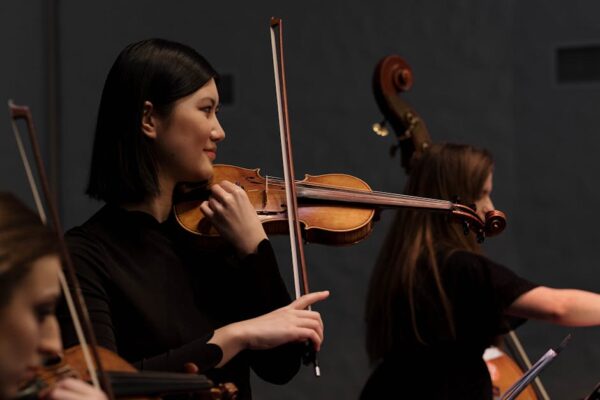 Asian female violinist performing on stage during a live concert.