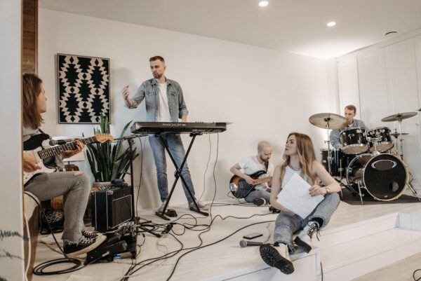 Group of young musicians practicing with instruments in a modern studio setting.