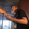 Dynamic indoor guitarist performance captured from a low angle, showcasing music passion.