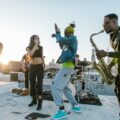 Vibrant music group performing live on a rooftop, showcasing diverse instruments and energetic moves.