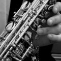 Monochrome image highlighting a musician's hand playing a saxophone, emphasizing musical artistry.