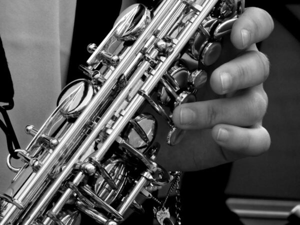 Monochrome image highlighting a musician's hand playing a saxophone, emphasizing musical artistry.