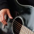 Detailed view of a person strumming an acoustic guitar, focusing on the guitar strings and hand.