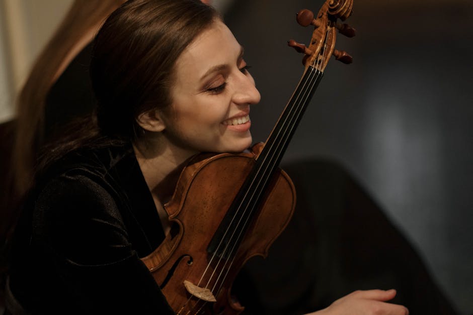 A joyful female violinist holding her violin closely, immersed in her music.