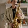 A young man passionately playing saxophone in a vintage kitchen setting.