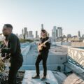 Indie band performing on a rooftop with the Los Angeles skyline at sunset.