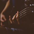 Moody close-up of a hand playing a guitar. Perfect for music-themed projects.