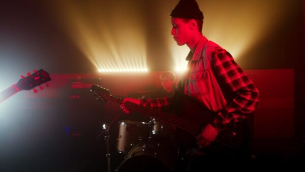 Energetic live band performance with guitarist and drummer under vibrant stage lights.