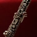 Detailed close-up of an oboe with intricate keys set against a rich red background, highlighting its elegance.