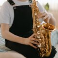 A young musician playing the saxophone indoors, focusing on musical expression.