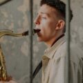 Young musician playing saxophone indoors, showcasing talent and passion.