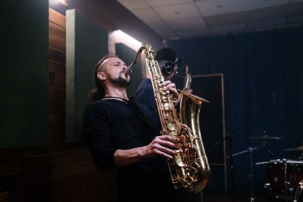 Musician playing saxophone passionately in an indoor recording studio setting.