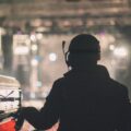 Sound engineer managing audio equipment at a live concert in Wuhan, silhouetted against bright stage lights.