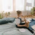 A young girl practices the saxophone in a cozy indoor setting, surrounded by musical sheets and plants.