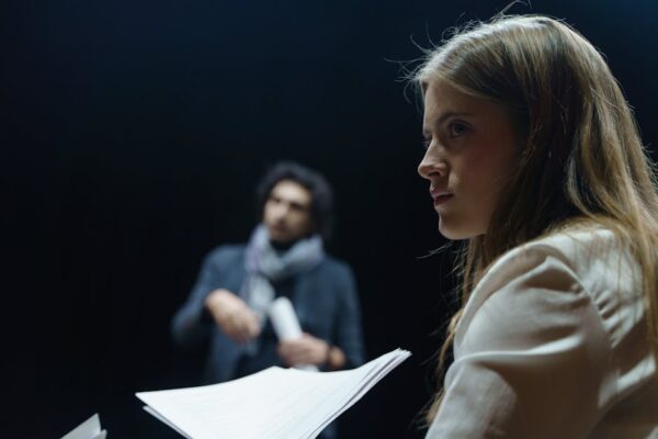 Actors rehearsing a scene with focus on character development and script analysis in a theater setting.