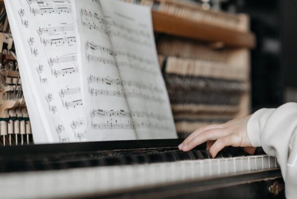 Close-up of child playing piano with sheet music. Focus on keys and notes.
