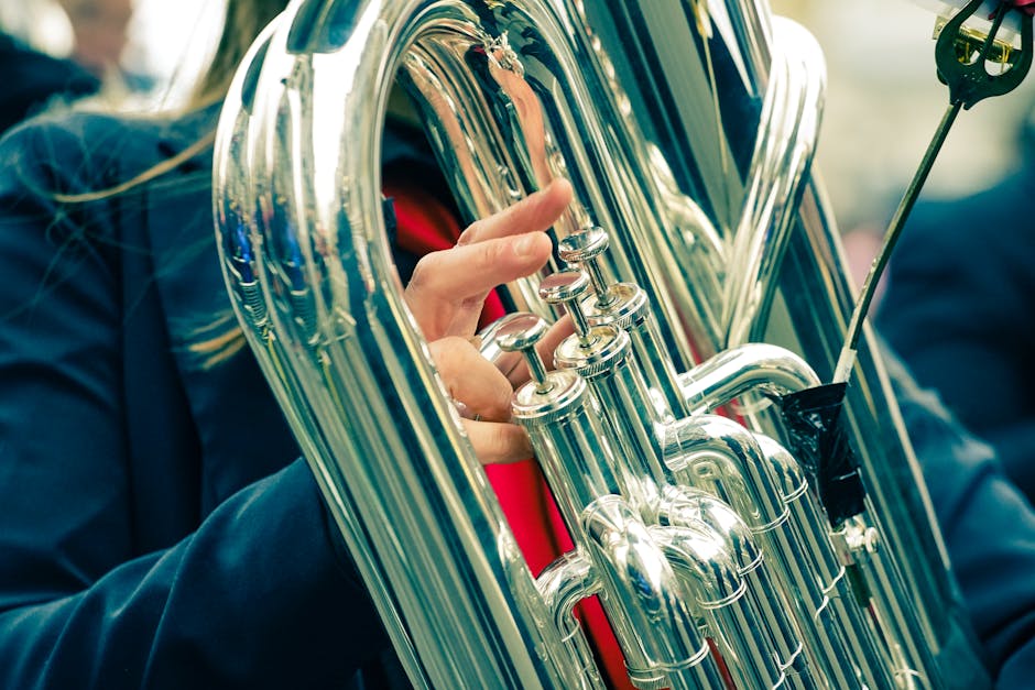 Close-up of a musician's hand playing a euphonium during an outdoor performance.
