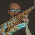 Musician with sunglasses performing jazz on a saxophone, creating a soulful vibe.