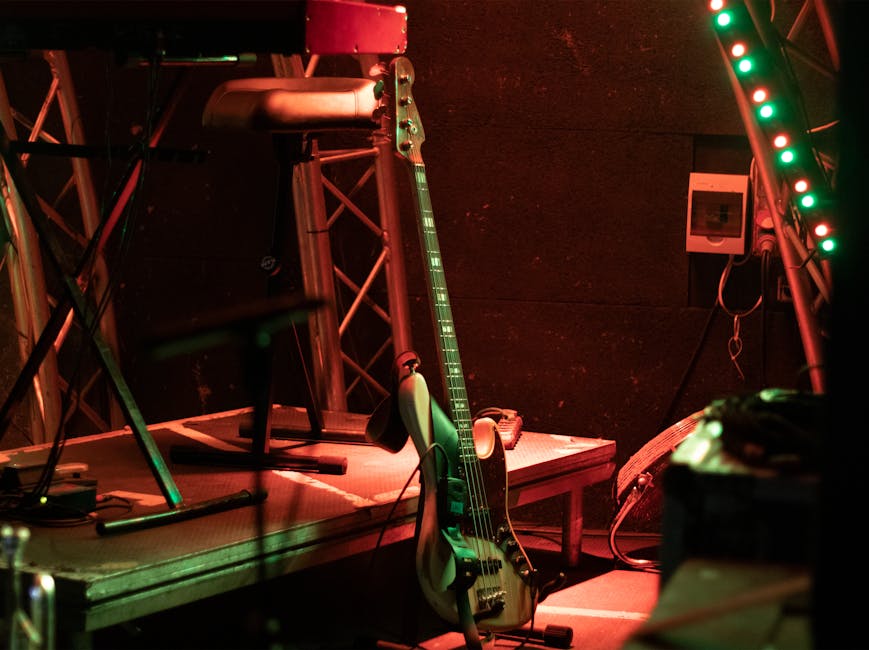 An atmospheric stage with a bass guitar and vibrant strip lights, ready for a live performance.