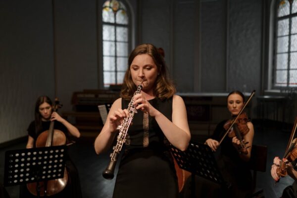 A woman playing the oboe during a classical music concert indoors.