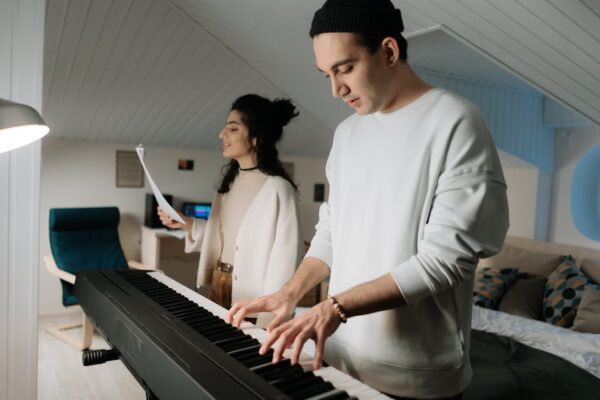 Man playing piano as a woman sings in a cozy, modern living room.