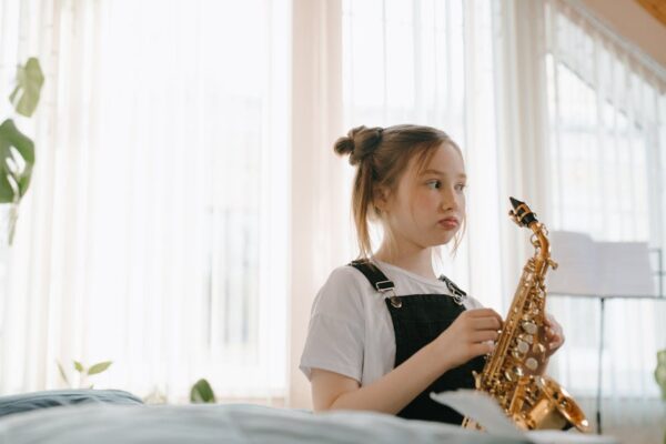 A young girl practicing saxophone indoors, capturing the essence of musical learning.