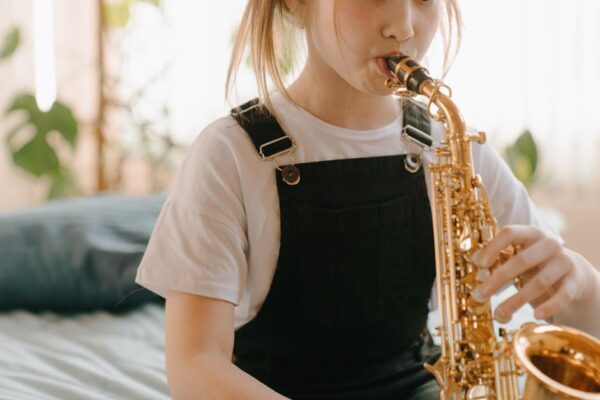 A young girl plays the saxophone indoors, showcasing musical talent.