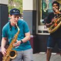 Musicians performing with saxophone and tuba on a city street.