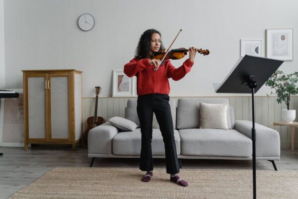 Young woman practicing violin in stylish living room, creating an artistic and musical atmosphere.