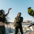 Energetic outdoor rooftop performance with diverse musicians playing instruments.