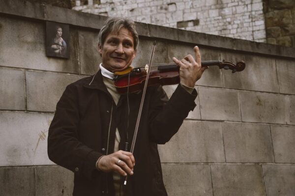 Street musician playing the violin against a brick wall backdrop, conveying a classic artistic vibe.