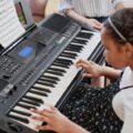 African American girl playing the keyboard indoors, practicing music.