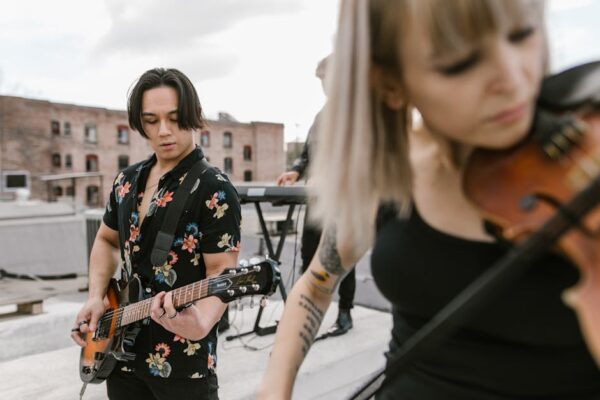A vibrant outdoor music performance featuring guitar and violin on an urban rooftop.