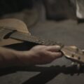Artistic close-up of a hand holding a vintage ukulele, showcasing intricate details and warm tones.