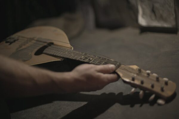 Artistic close-up of a hand holding a vintage ukulele, showcasing intricate details and warm tones.