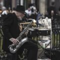 Elderly musician playing saxophone in Prague's lively streets, capturing the essence of street art.