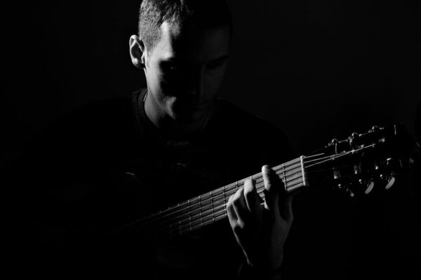 A captivating black and white portrait of a guitarist in an artistic pose, playing guitar.