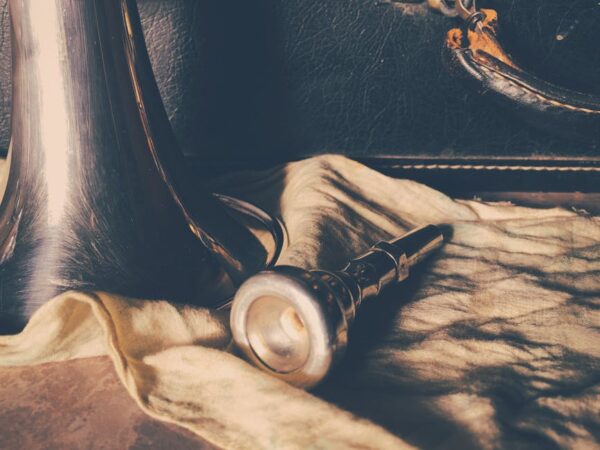 Artistic shot of a trumpet mouthpiece on fabric evokes a vintage musical feel.