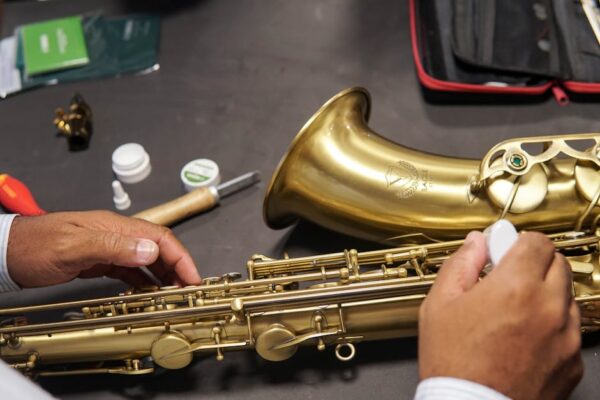 A detailed view showing a saxophone being repaired by skilled hands, emphasizing craftsmanship.