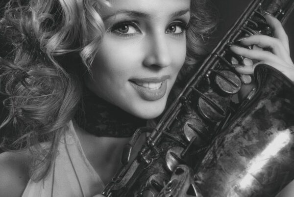 Elegant black and white portrait featuring a woman holding a saxophone with a radiant smile.