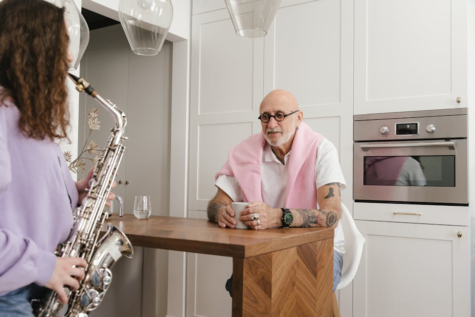 A young woman plays saxophone in a kitchen while an elderly man listens with interest.