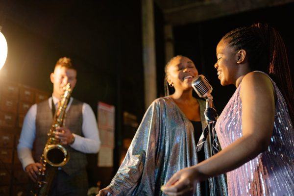Energetic jazz performance with female singers and saxophonist on stage.