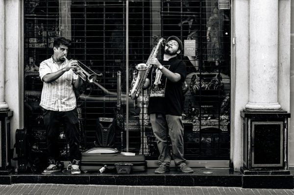 Two street musicians playing trumpet and saxophone in Buenos Aires, creating a lively urban scene.