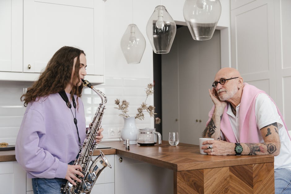Young saxophonist playing music in a modern kitchen with an elderly listener.