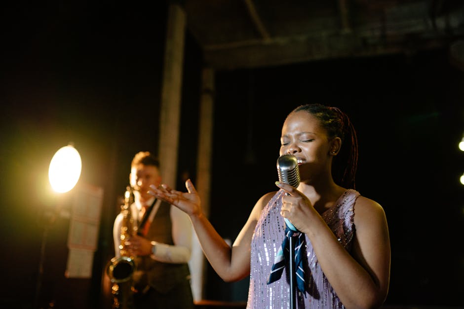 Captivating jazz singer performing live with saxophonist on stage in low light setting.