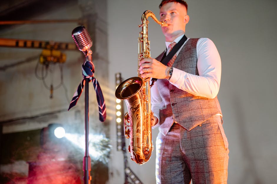 A saxophonist playing live music indoors with a vintage microphone on stage.